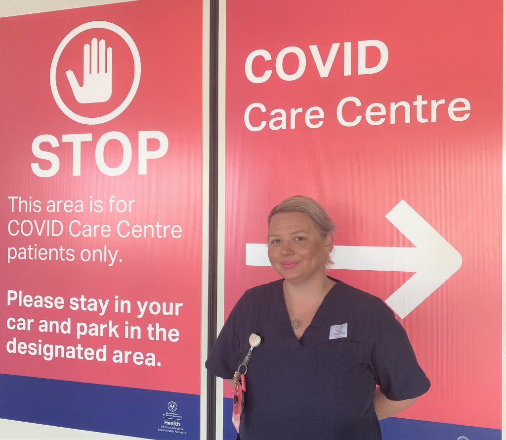 Nurse standing in front of sign saying COVID Care Centre