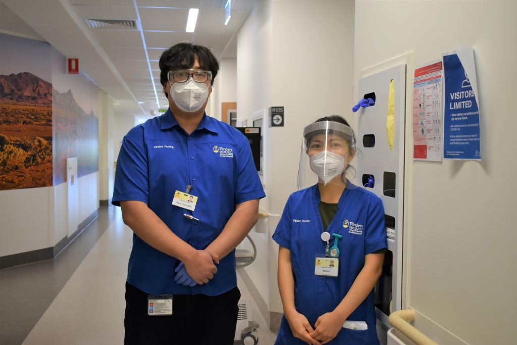 Two student nurses standing a hospital corridor looking at the camera