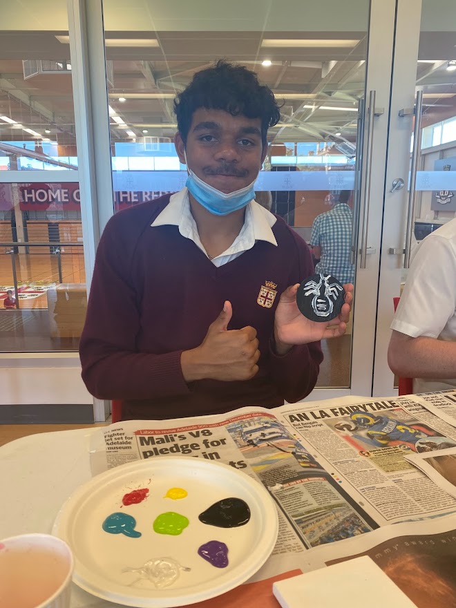 Student giving thumbs up while showing painting of honey ant. 