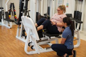 Patient doing leg press exercise supervised by physiotherapist