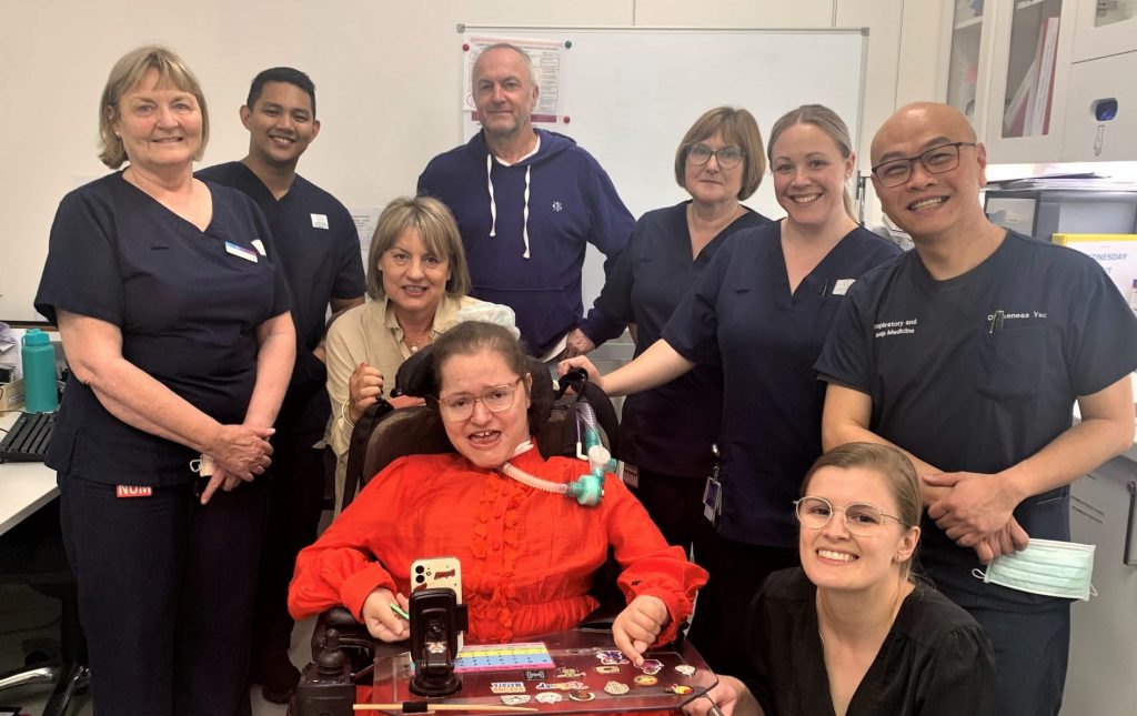 Patient Alice in a fabulous orange dress, surrounded by her patients and healthcare team at the RAH.